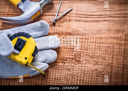 Gelbes Roulette in Schutzhandschuh Hammer Nägel auf Vintage Holzbrett Konstruktion Konzept Stockfoto