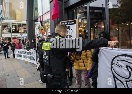 Berlin, Deutschland. 19.. November 2022. Aktivisten versammelten sich am 19. November 2022 in Berlin, um auf Menschenrechtsverletzungen in Katar aufmerksam zu machen. Die Aktivisten der Gruppe Extinction Rebellion blockierten den Eingang des Adidas-Flagship-Stores in der Tauentzienstraße, um gegen das Sponsoring der WM zu protestieren. Ein Transparent mit der Aufschrift ''#BoycottQatar2022'' rief die Öffentlichkeit dazu auf, keine Produkte aus der WM in Katar, wie den offiziellen Adidas-Spielball, zu kaufen und die Spiele nicht anzusehen. Mit der WM in Katar, massiven fossilen Emissionen, Menschenrechtsverletzungen und dem Tod von Gastarbeitern Stockfoto