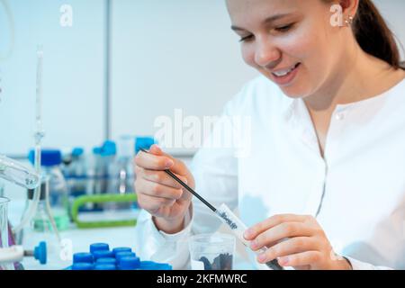 Bodenanalyse für schädliche Chemikalien in einem Agrarlabor nimmt eine junge Frau Bodenprosa aus einem Reagenzglas für die chemische Analyse Stockfoto
