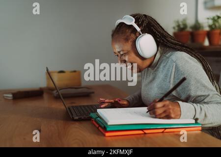 Ältere afrikanische Frau, die zu Hause an einem Laptop arbeitet – Smart Work and Technology Concept Stockfoto