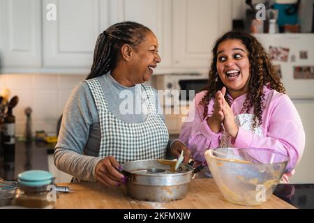 Glückliche afrikanische Mutter und Tochter, die ein hausgemachtes Dessert zubereiten Stockfoto