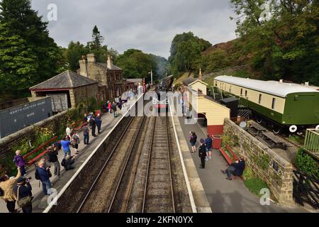 Eine geschäftige Szene am Bahnhof Goathland, North Yorkshire Moors Railway, als ein Dampfzug von Grosmont aus ankommt. (Siehe Hinweis). Stockfoto