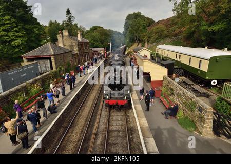 Eine geschäftige Szene am Bahnhof Goathland, North Yorkshire Moors Railway, als ein Dampfzug von Grosmont aus ankommt. (Siehe Hinweis). Stockfoto