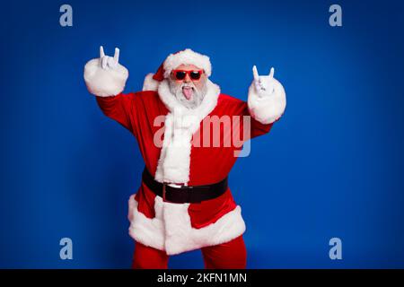Portrait von attraktiven verrückt fröhlich kindisch Santa zeigt Horn Symbol mit Spaß isoliert über hellen roten Hintergrund Stockfoto