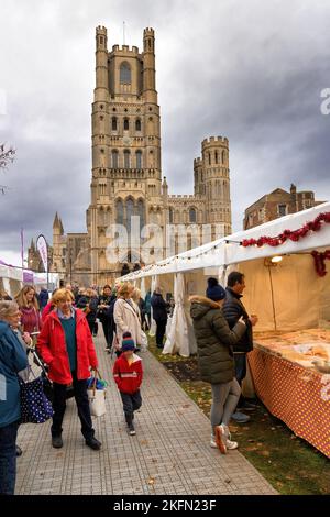 Ely UK; Ely Cathedral Weihnachtsmarkt - Leute, die draußen an den Essen- und Geschenkmarkt-Ständen in Xmas, Ely Cambridgeshire UK einkaufen Stockfoto