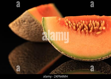 Nahaufnahme von frischer, saftiger Melone, die auf schwarzer Oberfläche reflektiert wird Stockfoto