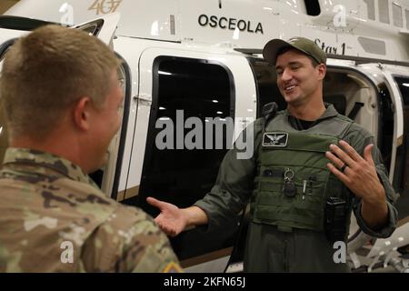 Stephen Kersey, ein Pilot beim Osceola Sheriff’s Department (rechts), erklärt SPC. Hunter Wolfe (links), Air Defense Battle Management Systems Operator mit der 1-265. Air Defense Artillery (ADA), die Bedeutung der Hubschrauberunterstützung während des HIANC in Kissimmee, Florida, 28. September 2022. Stephen Kersey erklärt, wie man einen Hubschrauber vor und nach einem Hurrikan zur Such- und Rettungsaktion pilotieren muss. Stephen wurde 2011 Pilot der Nationalgarde und diente seitdem bei jedem großen Hurrikan. Er sagt, dass er seine Fähigkeiten und seinen Erfolg im Leben seinem Dienst in Guar zuschreibt Stockfoto