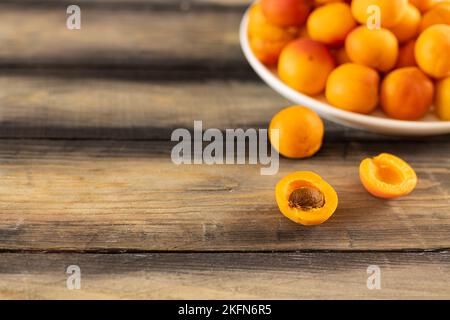 Frische Aprikosen. Reife saftige Aprikose in einem Teller auf einem Holztisch. Lose Aprikosen. Stockfoto