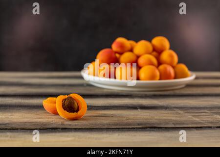 Frische Aprikosen. Reife saftige Aprikose in einem Teller auf einem Holztisch. Lose Aprikosen. Stockfoto