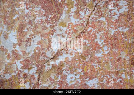 Großer Riss auf bemalten bunten verwitterten Wand mit Überresten von Farbe des alten Gebäudes, abstraktes Bild von Riss, Detail. Folgen des Erdbebens. Stockfoto