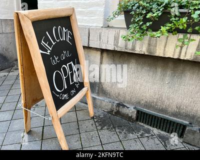 schild vor einem Geschäft oder Café Tür. Kreidetafel mit offenem Schild an der Straße, Eingang eines Geschäfts sagt willkommen, wir sind offen kommen auf schwarzen Boa Stockfoto