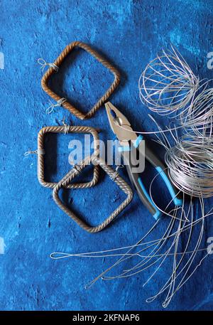 Vintage-Zange, Draht und Armierungsstahl auf blauem strukturiertem Hintergrund mit Kopierbereich. Renovierungsarbeiten im Detail. Stockfoto