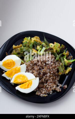 Buchweizenbrei mit gekochten Eiern, Gemüse und Brokkoli Stockfoto