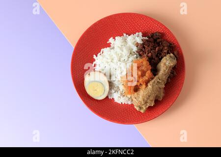 Nasi Gudeg, traditionelles Gericht aus Yogyakarta und Zentraljava, Indonesien. Weißer Reis gemischt mit Gudeg, Krecek, Ei und Hühnereintopf. Serviert auf Red P Stockfoto