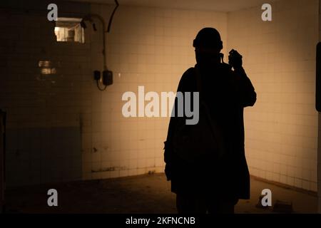 Umweltkatastrophe. Postapokalyptischer Überlebender in Gasmaske auf dunklem Hintergrund, Beleuchtung Taschenlampe. Dramatischer Mann mit Gasmaske. Stockfoto