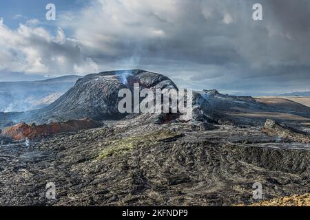 Vulkanlandschaft in Island auf der Halbinsel Reykjanes. Dampf steigt aus dem Vulkan auf. Wolken am Himmel mit Sonnenschein. Aktiver Vulkankrater vor eru Stockfoto