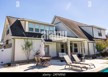 Die Seitenansicht eines langen Handwerkerhauses in weißem cremefarbenen Neubau mit überdachtem Terrassenbereich Stockfoto