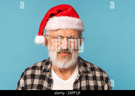 Düsteres Weihnachtsmann-Porträt vor blauem Hintergrund mit Kopierraum. Wirtschaftskrise und Probleme Ende des Jahres Stockfoto