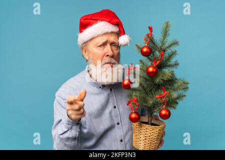 Düsteres Weihnachtsmann-Porträt vor blauem Hintergrund. Wirtschaftskrise und Probleme zum Jahresende Stockfoto