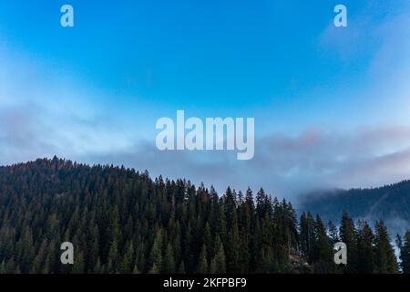 Berg atmosphärische Landschaft von hohen Bergen in dichtem Nebel bei regnerischem Wetter, Panorama von Berggipfeln in dicken Wolken, Morgendämmerung in den Bergen in EA Stockfoto