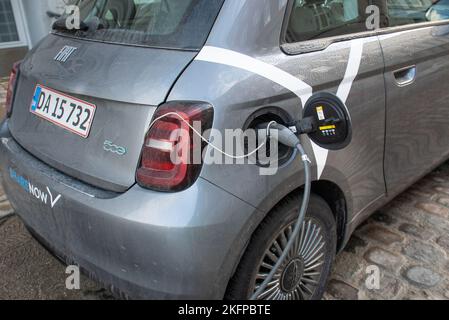 Aufladen von Elektroautos: Ein Fiat 500-Auto, das seine Batterie an einer Ladestation in Kopenhagen, Dänemark, Europa auflädt. Nachhaltiger Verkehr. Stockfoto