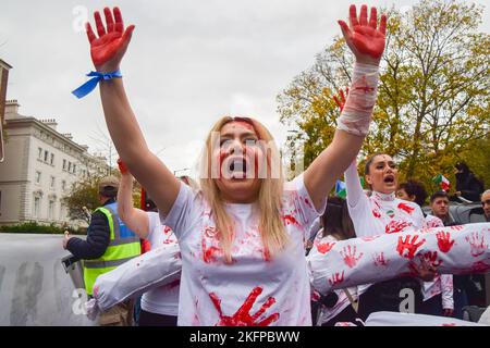 London, England, Großbritannien. 19.. November 2022. Eine Frau, die mit gefälschtem Blut bedeckt ist, hält ihre blutigen Hände hoch. Demonstranten versammelten sich vor der iranischen Botschaft und forderten Gerechtigkeit für Mahsa Amini und andere Opfer, einen Regimewechsel und Freiheit für den Iran. (Bild: © Vuk Valcic/ZUMA Press Wire) Stockfoto