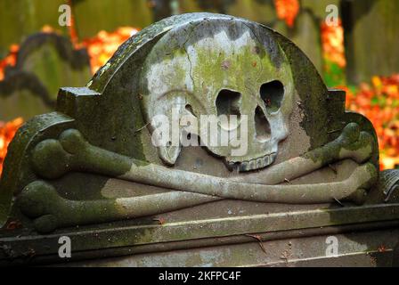 Ein Schädel und ein Kreuz ähneln einer Piratenflagge und sind in einen Grabstein und einen historischen Grabstein auf dem Grabenfriedhof von Granary gemeißelt Stockfoto