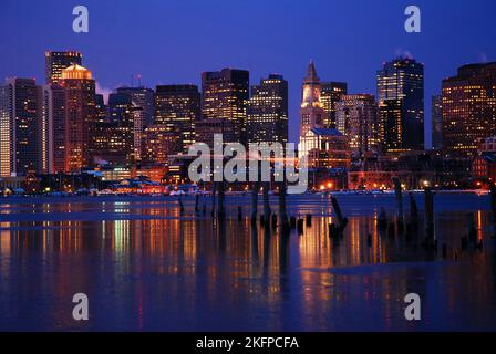 Die Lichter der Skyline von Boston und die Geschäfte spiegeln sich im eisigen Wasser des Hafens wider Stockfoto