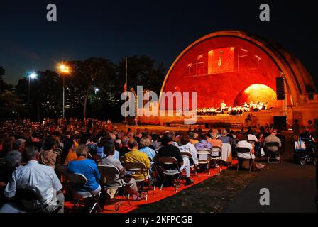 Im beleuchteten Hatch Shell in Boston spielt abends ein Konzert eines Symphonieorchesters klassische Musik Stockfoto