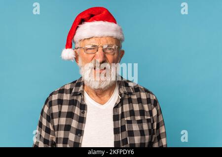 Düsteres Weihnachtsmann-Porträt vor blauem Hintergrund mit Kopierbereich. Wirtschaftskrise und Probleme zum Jahresende Stockfoto
