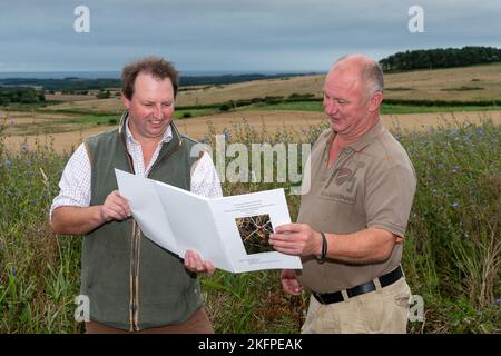 Landagent und Landwirt diskutieren über die Betriebsführung auf einem Ackerbaubetrieb in Northumberland, Großbritannien. Stockfoto