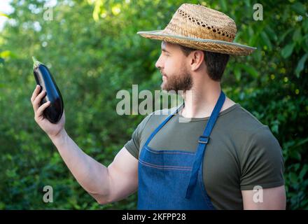 Mann Gemüsehändler in Strohhut hält Auberginen Gemüse Stockfoto