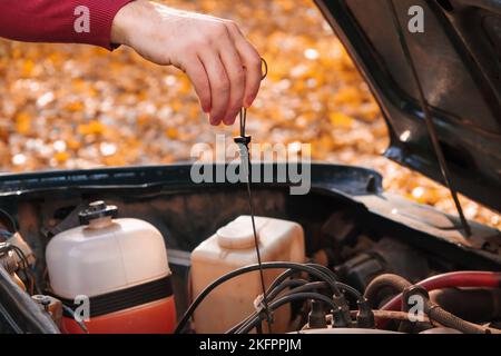 Ein Mann überprüft den Ölstand im Automotor. Selbstbedienung des Autos. Regelmäßige Überprüfung des Ölstands im Motor. Stockfoto