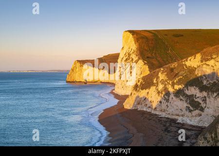 An einem kalten, klaren Morgen erhellt die Sonne am frühen Morgen die Kreidefelsen von Swyre Head und Bats Head an der Durdle Door an der Dorset Jurassic Coast. Stockfoto