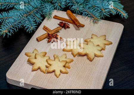 Frisch gebackene Zimt- und Vanille-Kekse in Schneeflockenform mit Weihnachtsschmuck Stockfoto