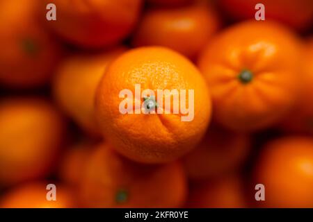Korb mit Mandarine oder orangen Früchten auf grauem karierten Hintergrund. Bio-Lebensmittel. Stockfoto