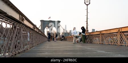 New York City, USA - 18. September 2022: Hübsche Menschen, die auf der Brooklyn Bridge spazieren und Fotos machen Stockfoto