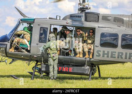 Das Batteriekommando und die Mitarbeiter der 1-265th Air Defense Artillery (ADA) besteigen einen UH-1 Irokesen, der von Mitgliedern des Charlotte Sheriff’s Department auf dem Weg geleitet wird, um eine Vermessung des Charlotte County durchzuführen und das Ausmaß der Zerstörung des Hurrikans Ian zu bewerten. Port Charlotte, Florida. Oktober 2022. Mehr als 6.000 Soldaten wurden als Reaktion auf die Naturkatastrophe aktiviert und sowohl militärische als auch zivile Unterstützung von außerstaatlichen Standorten. 22DoDHurricane, AlwaysThereAlwaysReady, HurricaneIan, Nationalgarde, Stockfoto