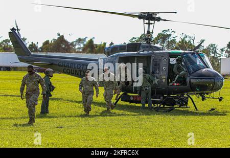 Das Batteriekommando und die Mitarbeiter der 1-265th Air Defense Artillery (ADA) lassen einen UH-1-Irokesen absteigen, der von Mitgliedern des Charlotte Sheriff’s Department gesteuert wurde. Port Charlotte, Florida. Oktober 2022. Mehr als 6.000 Soldaten wurden als Reaktion auf die Naturkatastrophe aktiviert und sowohl militärische als auch zivile Unterstützung von außerstaatlichen Standorten. 22DoDHurricane, AlwaysThereAlwaysReady, HurricaneIan, Nationalgarde, Stockfoto