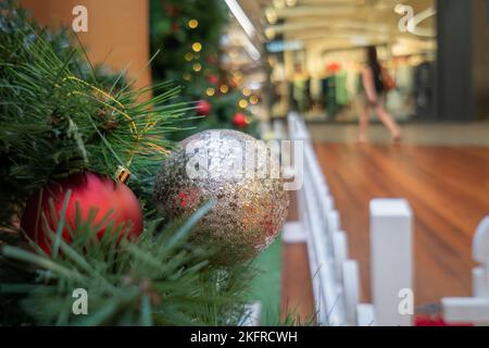 Einkaufszentrum in weihnachtlicher Dekoration, verschwommene Frau in Sommerkleidung, die durch die Geschäfte läuft. Auckland. Stockfoto