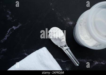 Waschpulver in Plastiklöffel auf schwarzem Hintergrund Stockfoto