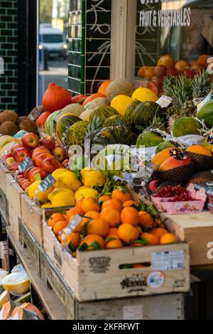 Sortierte Früchte und Gemüse auf Holzkisten, die auf einem Markt ausgestellt sind Stockfoto