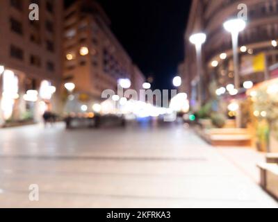 Unscharfer Hintergrund. Nachtstadt. Verschwommene Silhouette von Gebäuden, Bokeh-Flecken von leuchtenden Laternen. Verschwommener Blick auf die Stadtstraße.Bokeh-Effekt. Unschärfe-Unschärfe Stockfoto