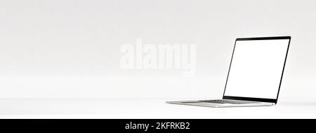 Laptop mit leerem Bildschirm auf weißem Tisch an weißer Wand. Seitenansicht des Laptops mit weißem, leerem Bildschirm. Moderner Computer-Laptop auf weißem Hintergrund f Stockfoto