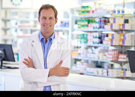 Die Gesundheit meiner Kunden ist von größter Bedeutung. Porträt eines hübschen Apothekers, der an der Rezeptheke steht. Stockfoto