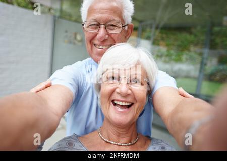 Liebe lässt deine Seele aus ihrem Versteck kriechen. Ein Seniorenpaar posiert für ein Selfie. Stockfoto