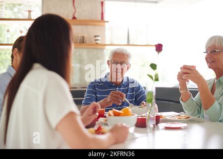 Essen schmeckt besser, wenn Sie es mit Ihrer Familie essen. Eine Familie sitzt zusammen am Esstisch. Stockfoto