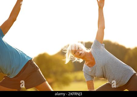 Flexibel bleiben. Ein reifes Paar macht gemeinsam Yoga im Freien. Stockfoto