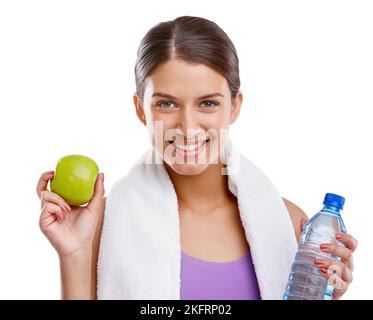 Eine schöne junge Frau, die einen frischen grünen Apfel und eine Flasche Wasser in der Hand hält. Stockfoto