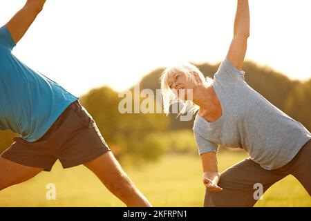 Ein reifes Paar macht gemeinsam Yoga im Freien. Stockfoto